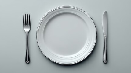 Clean white dinner plate with silver fork and knife on neutral gray background with soft shadows forming minimal lifestyle composition