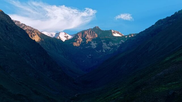 Aerial view establishing in 70mm cinematic shot of the summit of El Pomo hill with a small river between mountains in the shape of a box, sunrise light with bluish color.