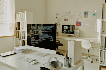Office of IT company fully equipped with snow white office furniture, digital devices and shelves for documents, room illumed by warm sunrays