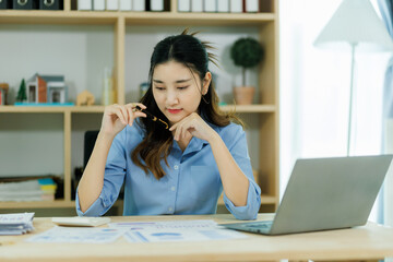 An Asian woman employee focused on completing the monthly sales summary with dedication.