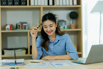 An Asian woman employee focused on completing the monthly sales summary with dedication.