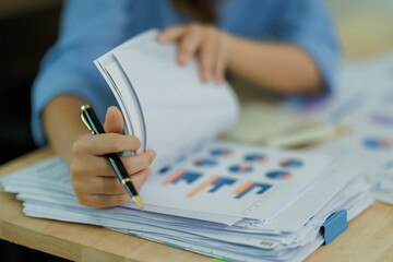 An Asian woman employee focused on completing the monthly sales summary with dedication.