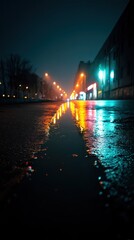 Fototapeta premium Rain-drenched city street at night showcases colorful reflections from streetlights. The road shines under a calm atmosphere, with moisture enhancing the urban scene's beauty