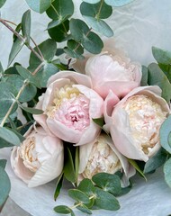 Bouquet of fresh peonies and eucalyptus in the white wrapping 