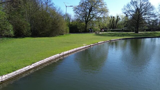 Drone view of a beautiful park and water pond in Brussels in a calm spring with horses walking around
