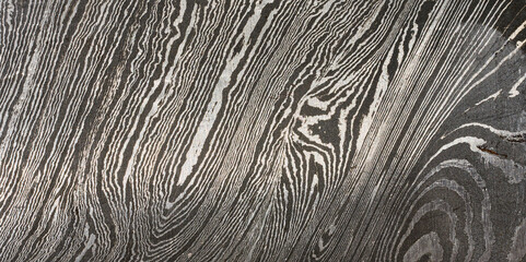 Detailed close up of damascus steel, showcasing its characteristic wavy and layered pattern of...