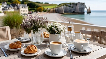 Fototapeta premium Scenic Breakfast Table by the Sea with Coffee, Pastries, Flowers and Stunning Coastal View