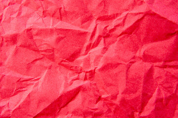 Fototapeta premium A close-up, top-down shot showcases the crinkled and uneven texture of bright red paper. Background concept.