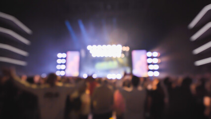 Crowd enjoying live music concert with bright lights shining on stage