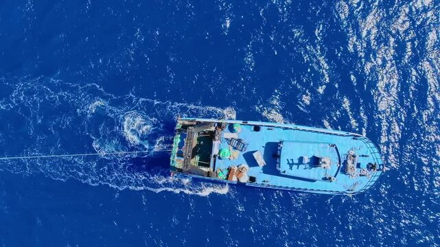 Aerial view of vibrant maltese fishing boat navigating open blue waters