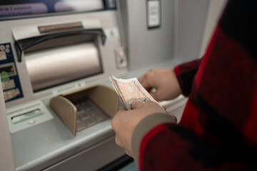 Obraz premium A close-up shot of a man withdrawing cash from an ATM, highlighting the transaction process. A moment of everyday banking, showing the use of technology in personal finance