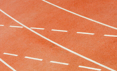 White lines marking running tracks on red surface of outdoor stadium
