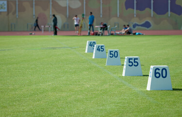 Distance markers line a green playing field during track and field event