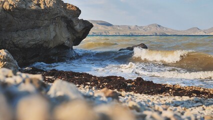 Powerful waves smashing rocky crimean coastline, rugged mountains looming across dark black sea...