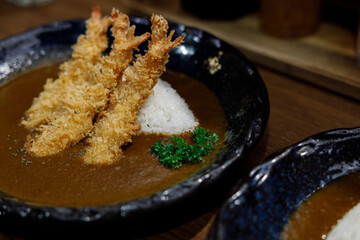 Delicious Japanese style curry rice topped with deep fried shrimp on plate.