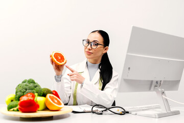 A nutritionist at a table with fruit, holding a grapefruit in a modern clinic office. The concept...