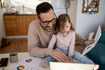 Father working from home with daughter on his lap using laptop