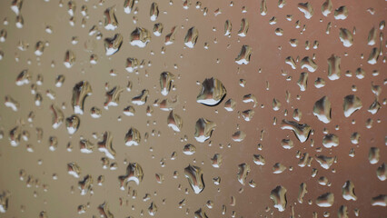 Raindrops sliding on a window during a rainy day reflecting a building