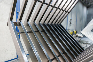 Obraz premium Pièce métallique suspendue par des câbles dans un entrepôt, en cours de traitement de thermolaquage par une entreprise spécialisée.