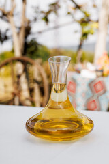 Wine decanter with white wine on a table set against a vineyard backdrop.