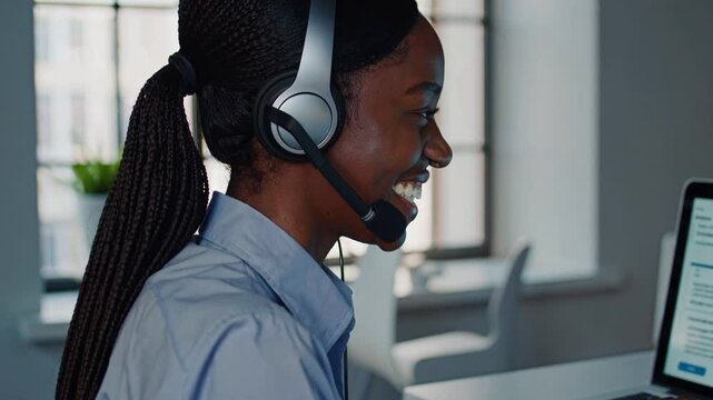 Corporate operator in headset working in customer support service on helpline telesale talking using laptop in business office. Agent of call center advises the client by answering questions. Close up