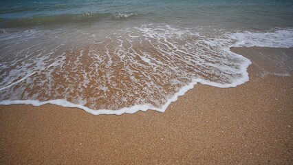 Soft wave gently washing golden sand on Crimean beach