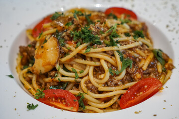 Close up view of a plate of Spaghetti Bolognese, a hearty pasta dish with a rich, meaty tomato sauce, commonly made with beef, onions, garlic, and herbs.