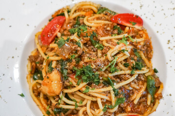 Close up view of a plate of Spaghetti Bolognese, a hearty pasta dish with a rich, meaty tomato sauce, commonly made with beef, onions, garlic, and herbs.