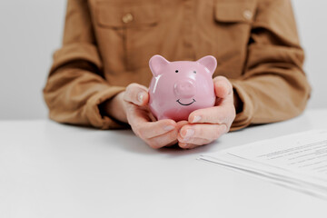 Person holds a pink piggy bank at a table with paperwork during a financial planning session