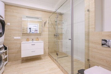 Modern bathroom featuring stacked washer dryer, vanity, and glass shower. Clean, contemporary design.