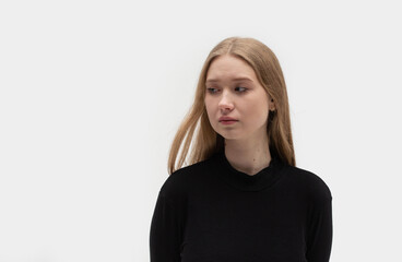 Obraz premium Portrait of a sad, miserable, desperate, grieving, crying blonde woman with tears eyes on a light black background during trouble, life difficulties, loss, and emotional problems.