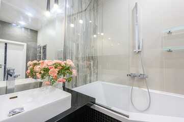 Modern bathroom featuring a white sink, bathtub, glass shower screen, and stylish gray & black...