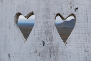 Two hearts carved in wood frame a distant landscape.