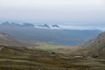 Icelandic valley with lake, mountains, and cloudy sky.