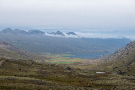 Icelandic valley with lake, mountains, and cloudy sky.