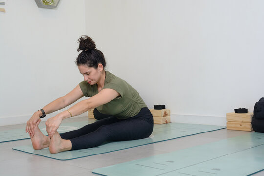 young woman on a mat doing leg and arm stretching exercises