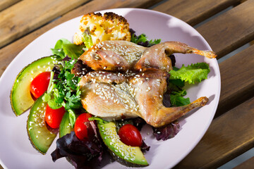 Quail-tobacco with sesame and salad of avocado is tasty dish in the kitchen.