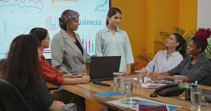 Indian asian happy senior boss woman project manager young adult expert girl lady get work indoor job office smiling proud leader talk hiring new intern staff join group team clap hands at place