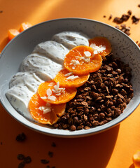 Granola with yogurt, fruits and nuts in a bowl. Chocolate granola with tangerine and yogurt