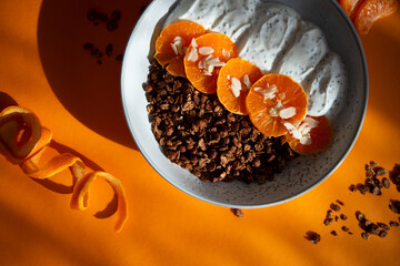 Granola with yogurt, fruits, chia seeds and nuts in a bowl. Chocolate granola with tangerine and yogurt, top view