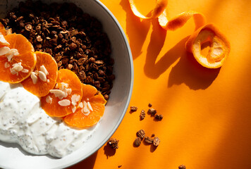 Granola with yogurt, fruits, chia seeds and nuts in a bowl. Chocolate granola with tangerine and yogurt, top view