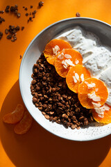 Granola with yogurt, fruits, chia seeds and nuts in a bowl. Chocolate granola with tangerine and yogurt, top view