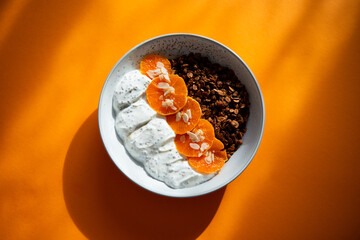 Granola with yogurt, fruits, chia seeds and nuts in a bowl. Chocolate granola with tangerine and yogurt, top view
