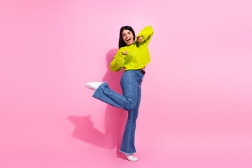 Cheerful young woman in casual colorful outfit posing enthusiastically against a bright pink...