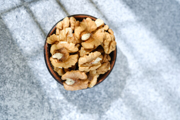 Bowl of healthy shelled walnuts on light stone background
