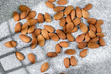 Scattered almonds on gray stone textured background