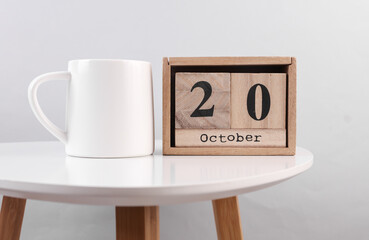 Wooden calendar organizer with date october 20 and ceramic cup on table