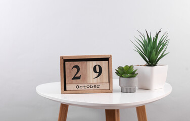Wooden calendar organizer with date october 29 and decorative plants on table