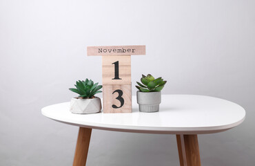 Wooden calendar organizer with date november 13 and decorative plants on table