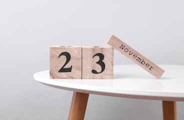 Wooden calendar organizer with date november 23 and decorative plant on table